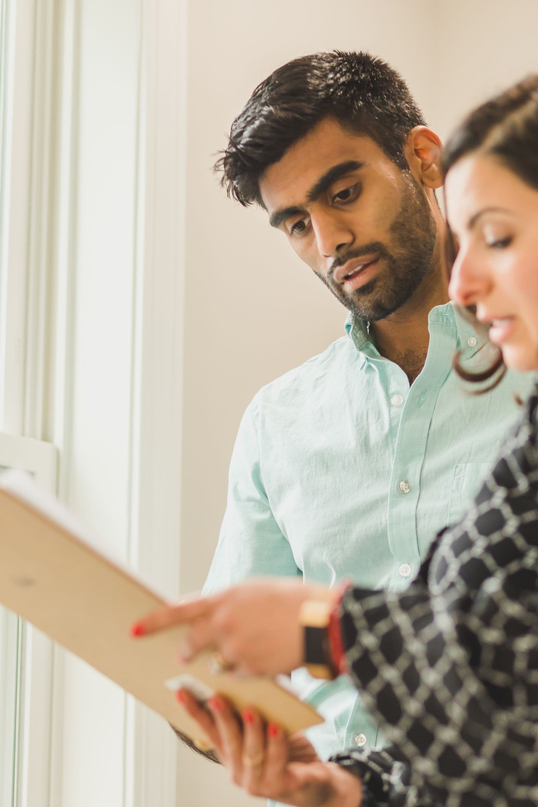 Two people look through a document on a clipboard together.